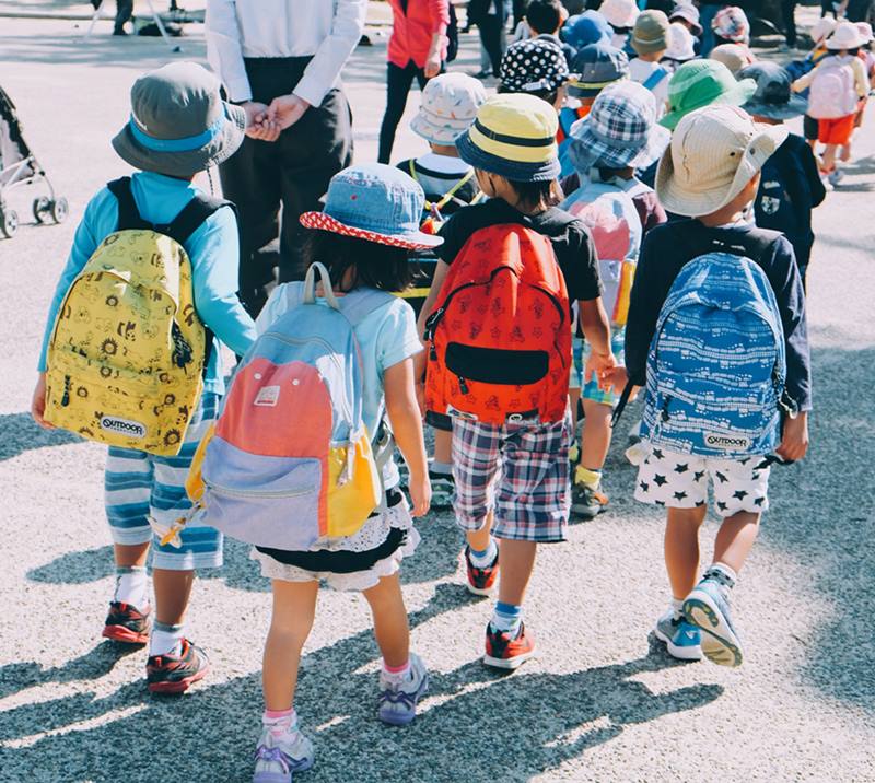 Crianças com mochilas nas costas caminhando em rua