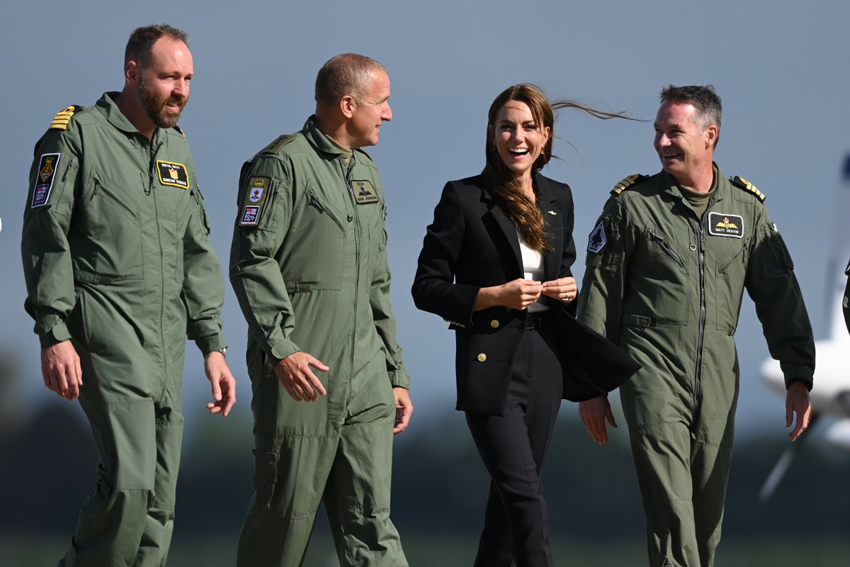 Foto colorida de três homens com roupas da aeronáutica ao lado de uma mulher branca, com cabelo longo e roupas pretas - Metrópoles