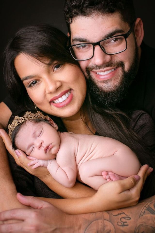 Foto colorida de um homem e uma mulher com um bebê - Metrópoles