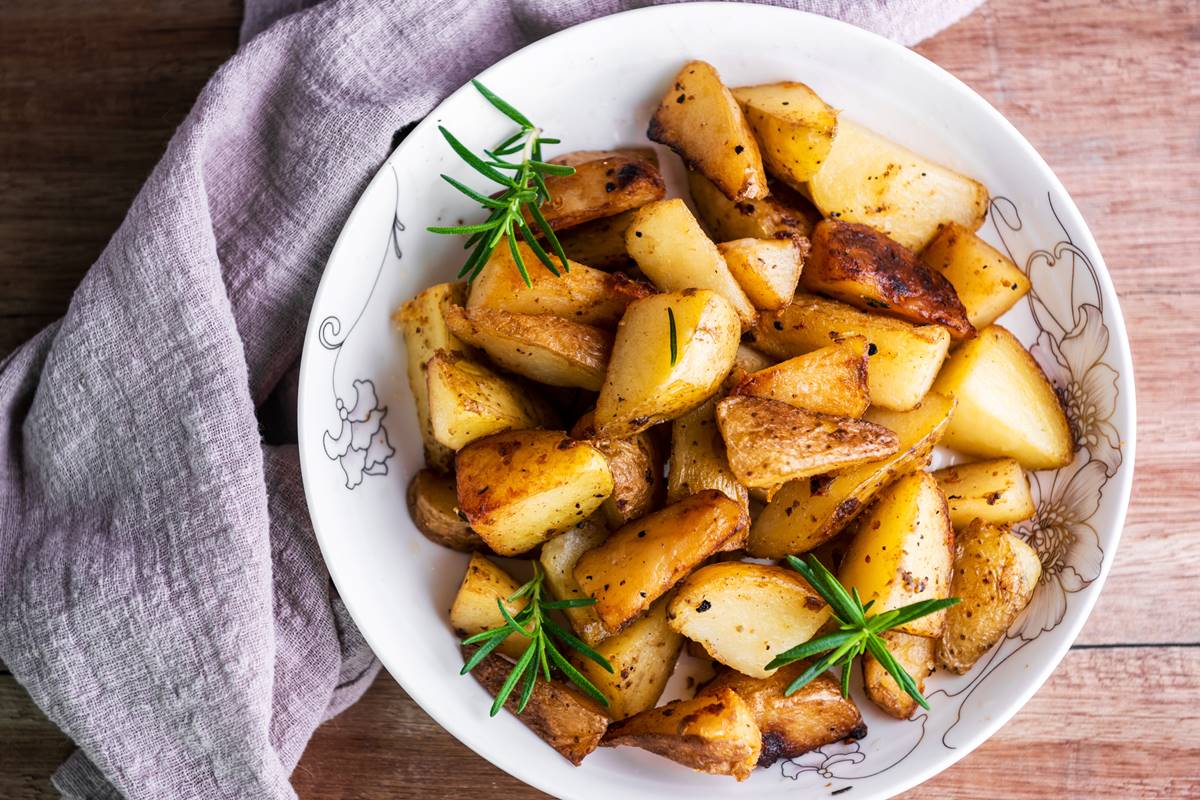 Foto colorida de prato branco com batatas assadas - Metrópoles