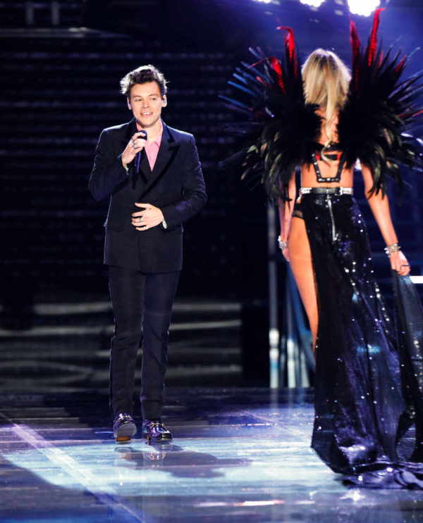 Na imagem com cor, Harry styles cantando no Victoria's Secret Fashion Show - Metrópoles