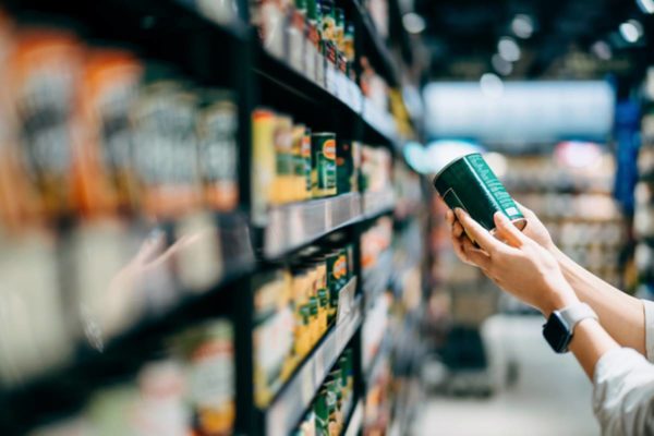 Imagem colorida de pesso lendo rótulo no supermercado - Metrópoles