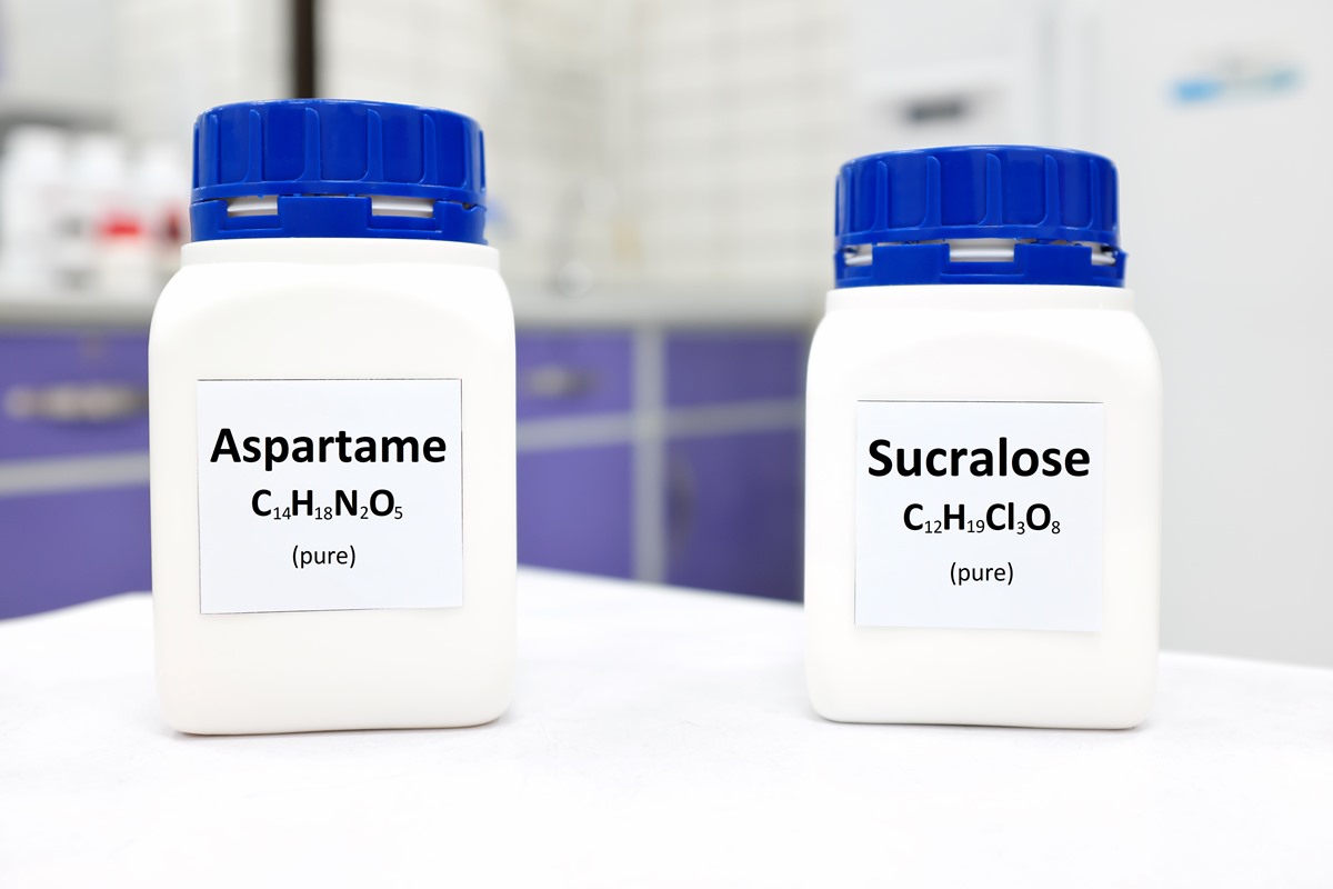 Imagem colorida. Duas embalagens brancas com tampa azul escrito. Uma está escrito "Aspartame" e a outra " Sucralose" - Metrópoles