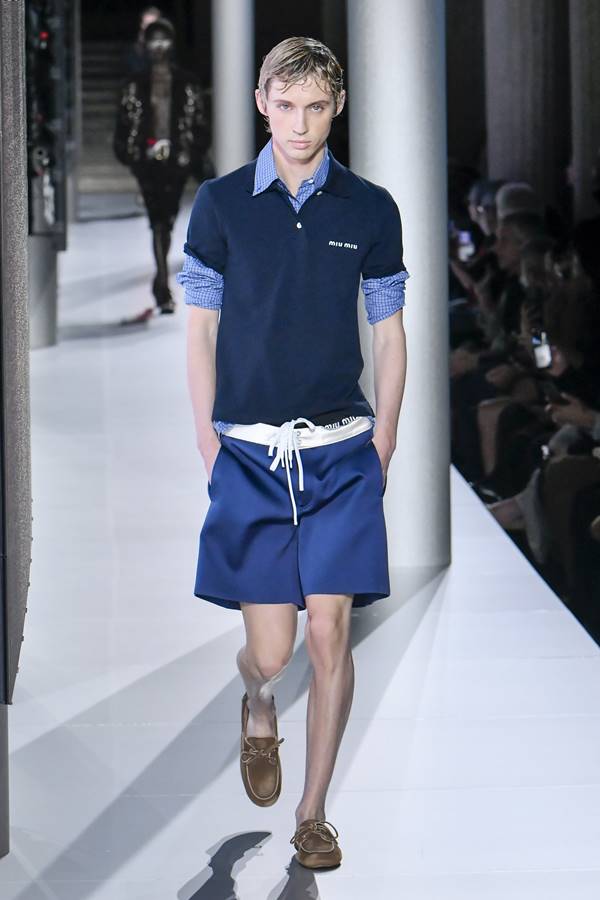 Troye Sivan na passarela da Miu Miu. Ele usa look azul com bermuda e camisa de gola pola - Metrópoles