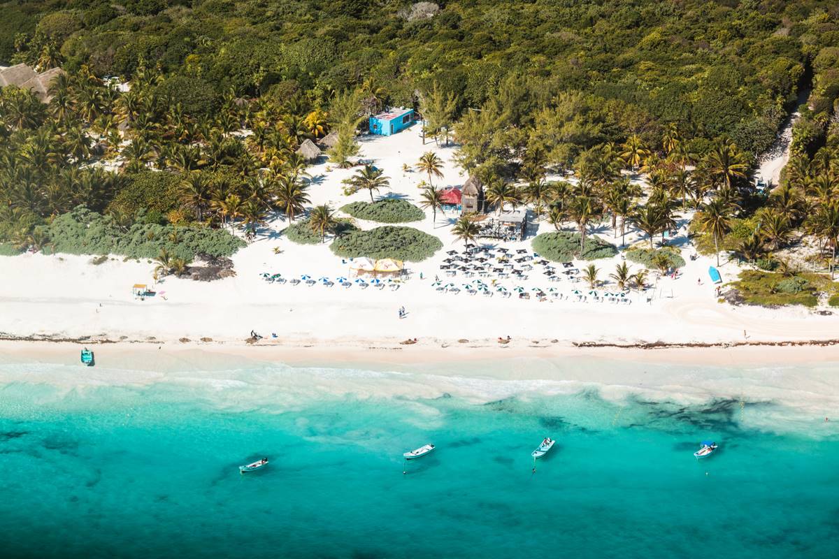 Foto colorida de vista panorâmica de praia com mar azul-turquesa - Metrópoles