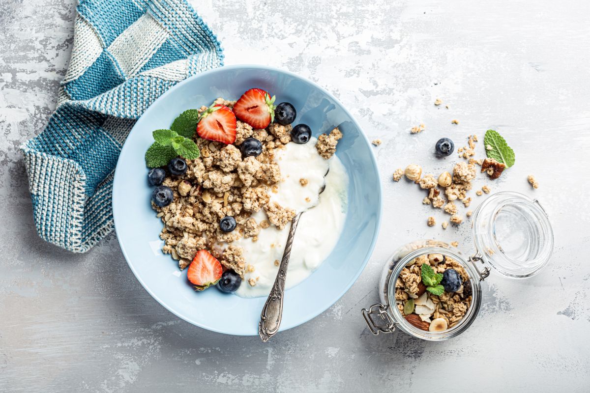 Tigela com iogurte, frutas e granola em mesa de café da manhã - Metrópoles