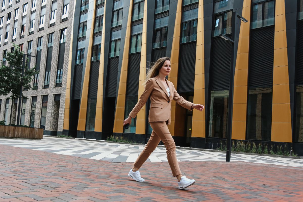 Jovem mulher caminhando em frente a um prédio na rua - Metrópoles