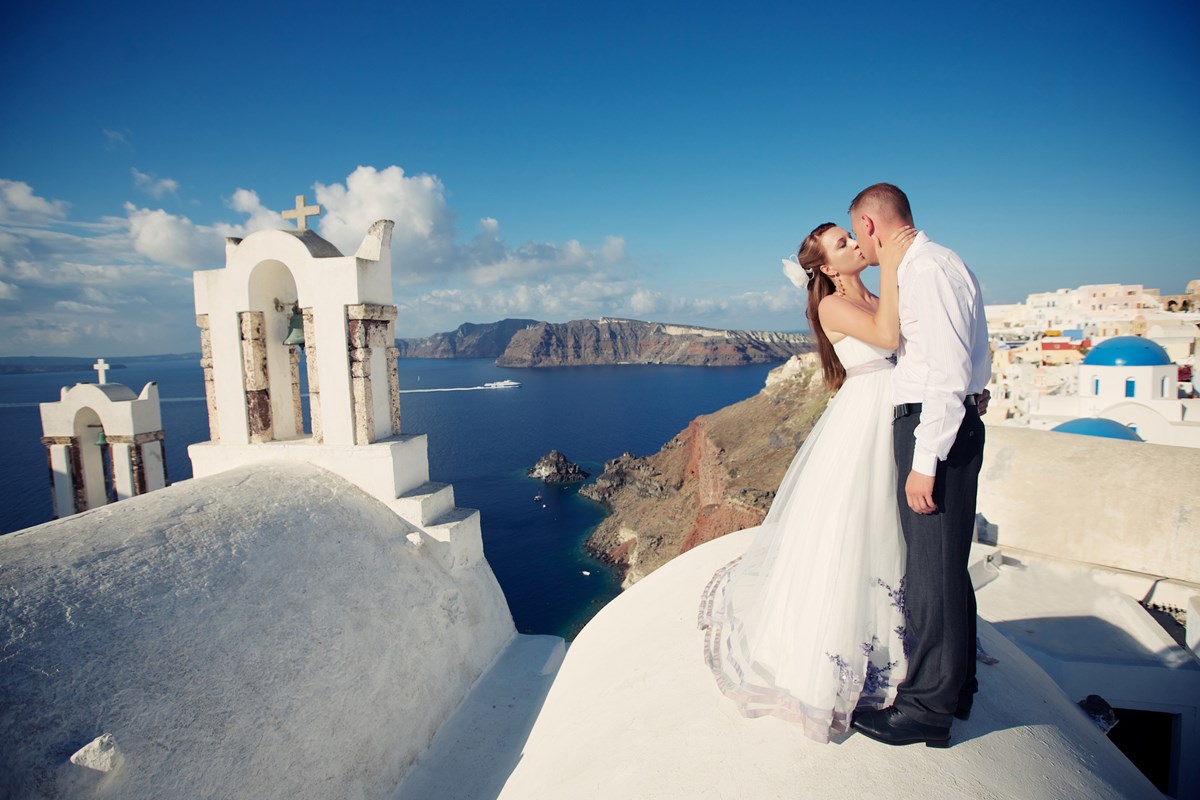 Foto colorida de casal se beijando em um lugar mais alto e com vista para o mar - Metrópoles