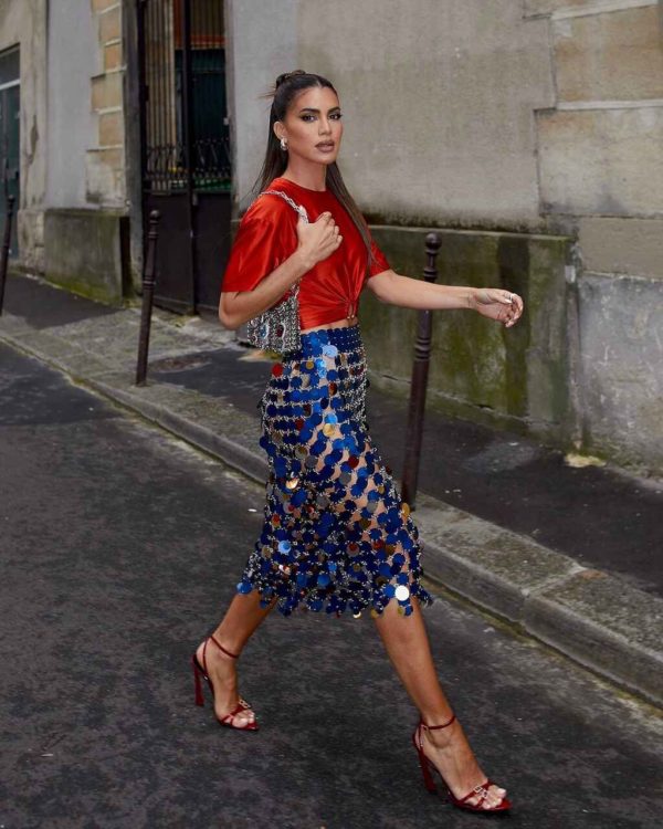 Na imagem com cor, uma mulher posando para foto com peças de roupa em vermelho - Metrópoles