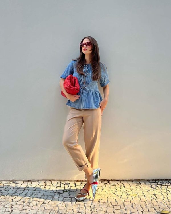 Na imagem com cor, uma mulher posando para foto com peças de roupa em vermelho - Metrópoles