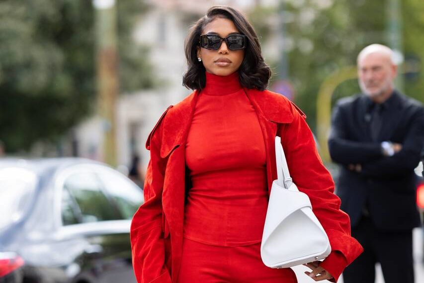 Na imagem com cor, uma mulher posando para foto com peças de roupa vermelhas - Metrópoles