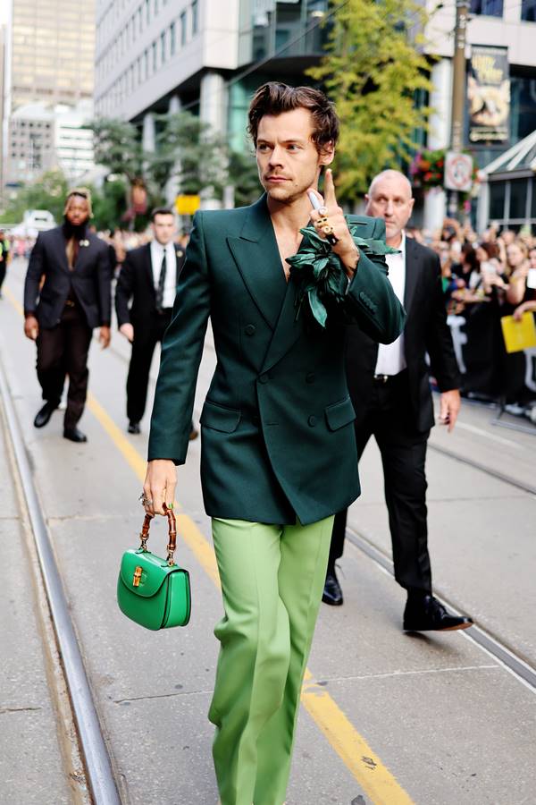 Na rua, o cantor Harry Styles usa look todo verde de alfaiataria com bolsa de mão que tem alça de bambu - Metrópoles