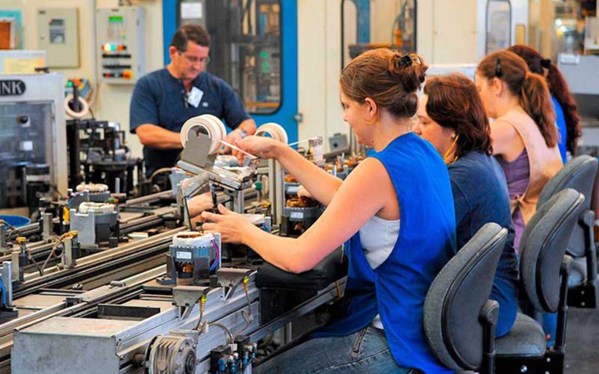Fotografia colorida mostrando mulheres costurando em fábrica-Metrópoles