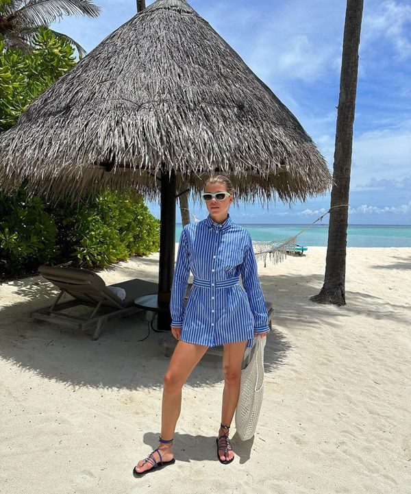 Na imagem com cor, Sofia Richie, mulher branca com cabelo loiro preso, posa na prata, usando peça única azul e óculos de sol brancos - Metrópoles