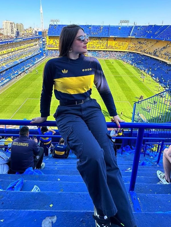 Mulher em estádio de futebol La Bombonera usando camisa do Boca Juniors e calça de alfaiataria preta - Metrópoles