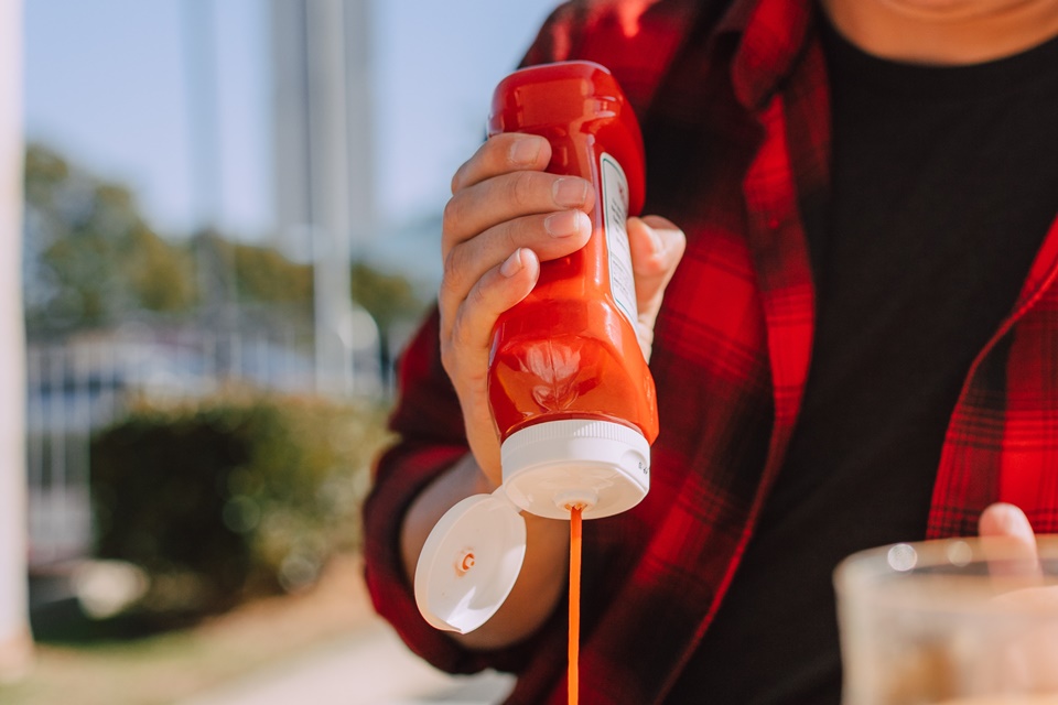 Jovem despejando ketchup em alimento - Metrópoles