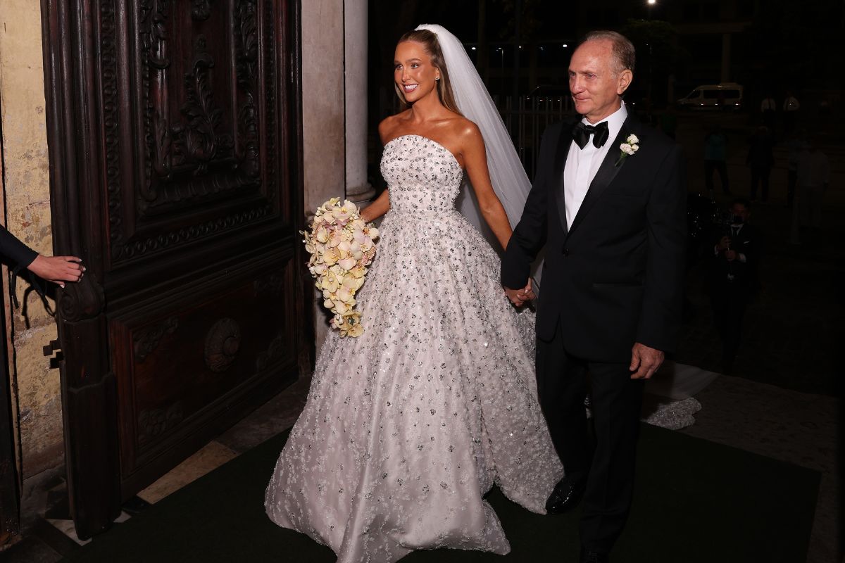 Paula Aziz entrando na igreja de mãos dadas com um senhor