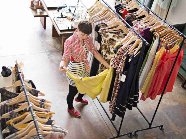 Na imagem com cor, uma mulher olhando roupas em uma loja de moda - Metrópoles