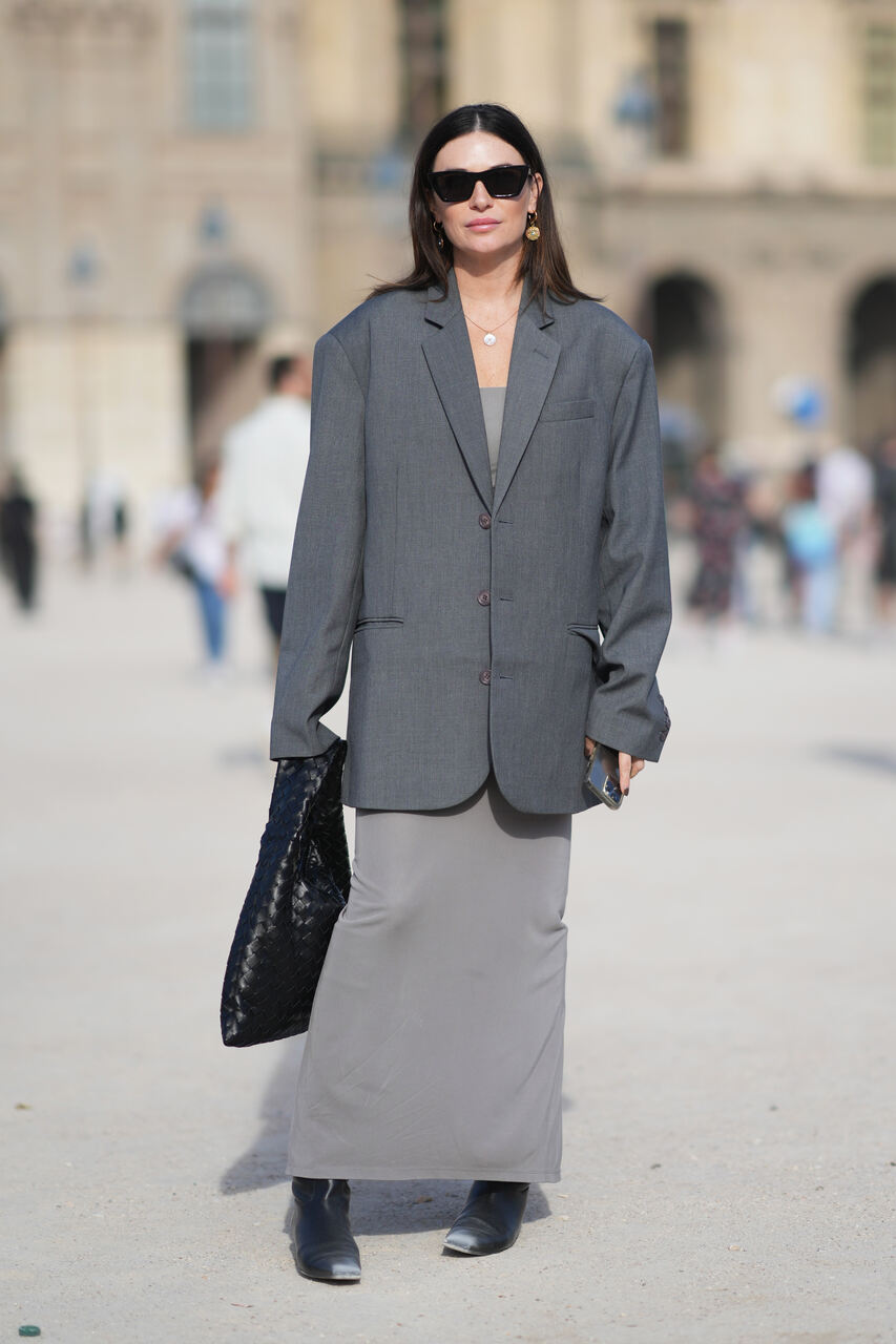 Na imagem com cor, uma mulher branca de cabelos pretosposando para foto com um look todo cinza - Metrópoles