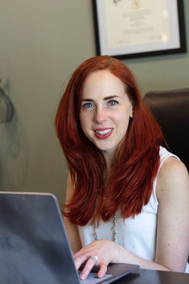 Foto colorida de mulher branca, ruiva e em frente a um notebook - Metrópoles