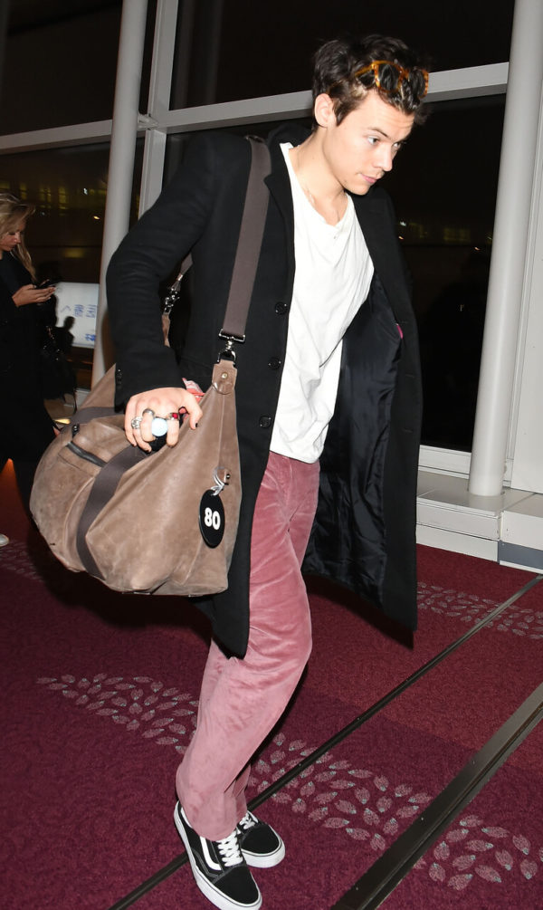 Na imagem com cor, Harry Styles andando no aeroporto com uma bagagem de mão em viagem - Metrópoles