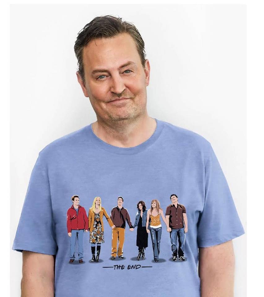 Foto colorida de Matthew Perry com uma camisa azul com estampa da série Friends e fundo branco