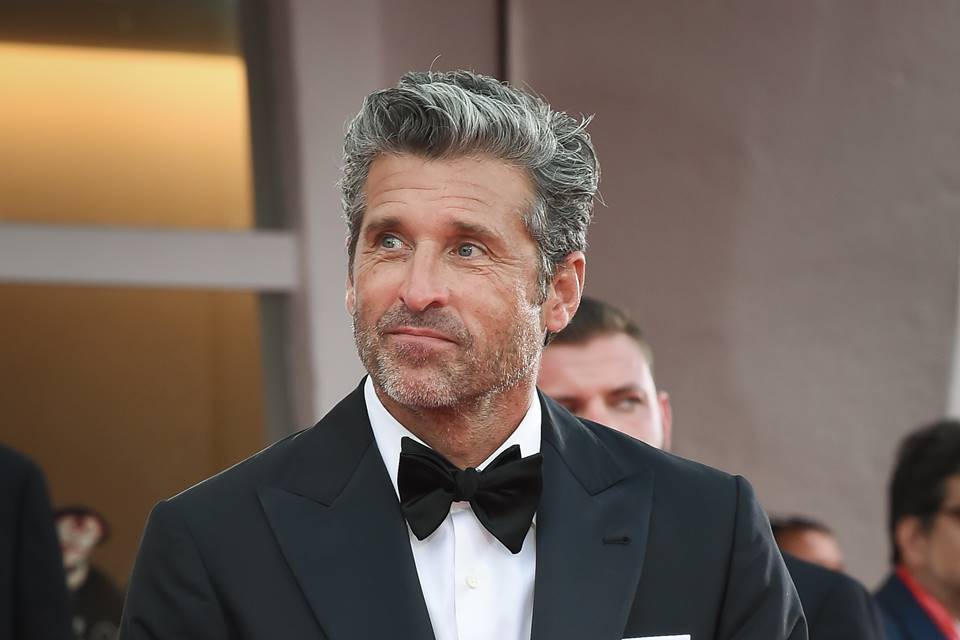 Foto colorida do ator Patrick Dempsey em premiação, olhando para o lado e usando terno - Metrópoles