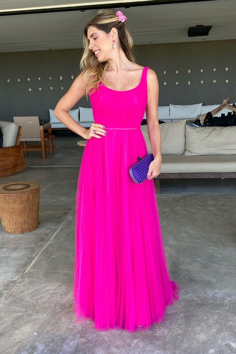 Foto colorida de mulher loira, posando para foto. Ela usa um vestido cor-de-rosa e clutch roxa - Metrópoles