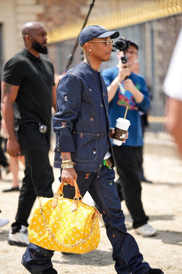 Na imagem com cor, Pharrell Williams andando durante o Paris Fashion Week com bolsa feita de pele de crocodilo - Metrópoles