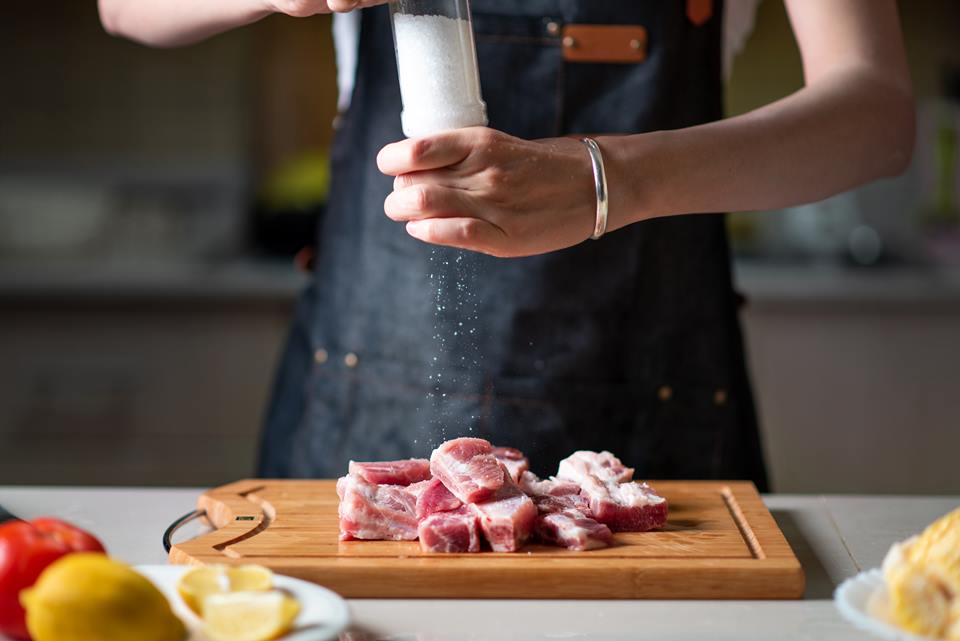 Mulher temperando carne - Metrópoles