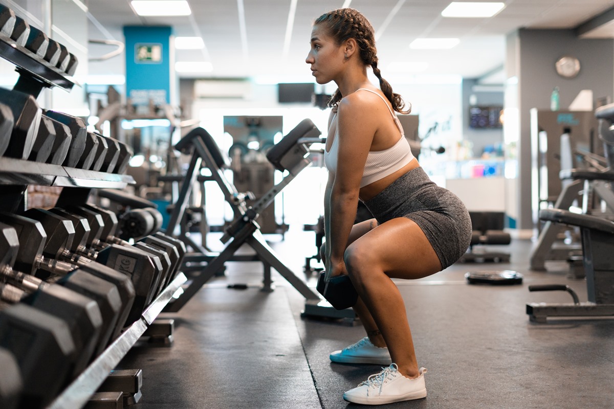 Mulher está usando roupa branca de academia e fazendo agachamento - metrópoles