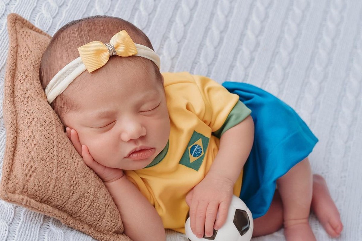 Foto colorida de bebê com blusa e shorts de uniforme da Seleção Brasileira - Metrópoles