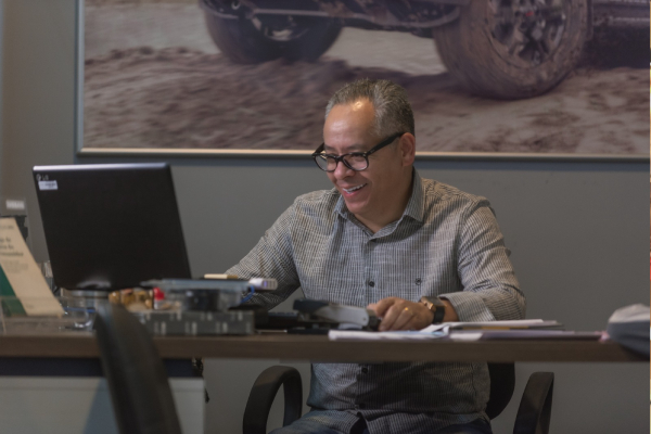 Foto colorida de um homem sentado em uma mesa mexendo no computador - Metrópoles 