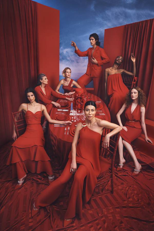 Em cenário vermelho, com mesa ao centro, modelos usam looks vermelhos - Metrópoles