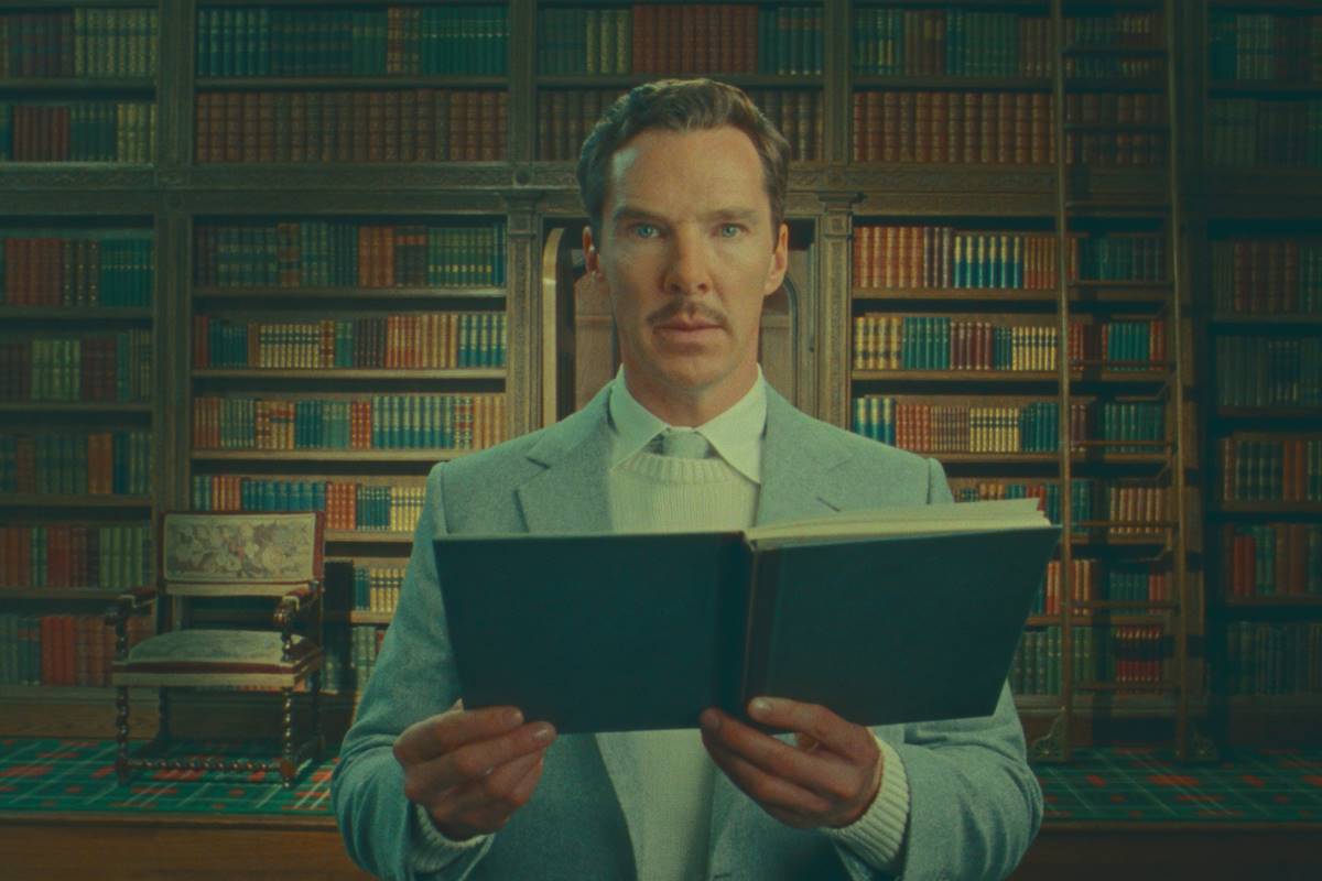Homem em biblioteca com um livro na mão - Metrópoles 