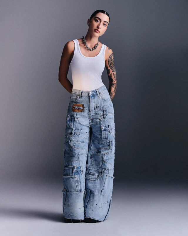 Mulher branca em campanha de moda. Ela usa regata branca e calça jeans com retalhos em patchwork - Metrópoles