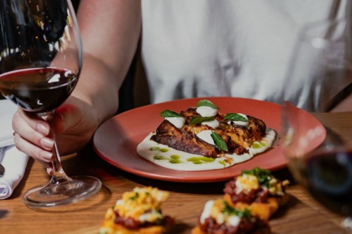 Foto colorida de um prato de comida e uma taça de vinho - Metrópoles