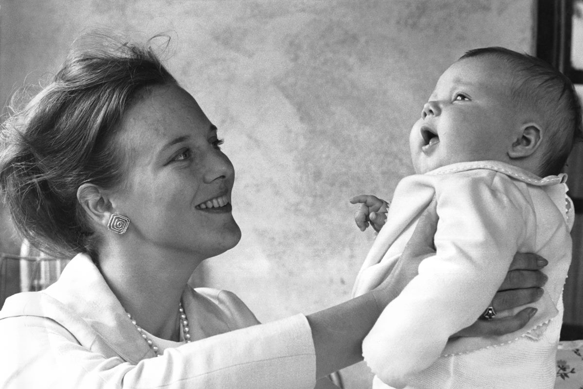 Foto em preto e branco de mulher segurando e levantando bebê no colo - Metrópoles