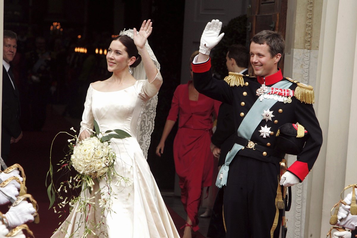 Foto colorida de mulher com vestido de noiva e homem com traje militar saindo de uma igreja - Metrópoles