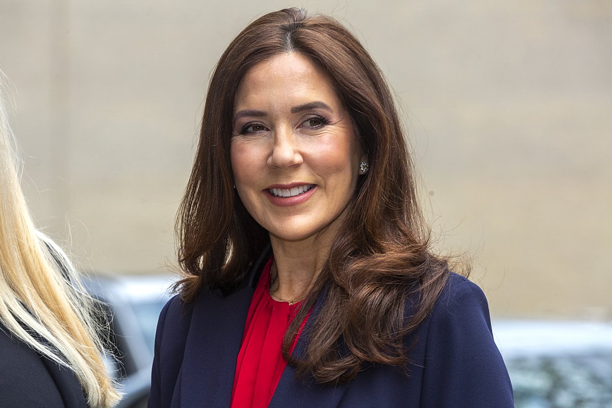 Foto colorida de mulher maquiada e com cabelo castanho. Ela usa blazer azul-escuro e blusa vermelha - Metrópoles