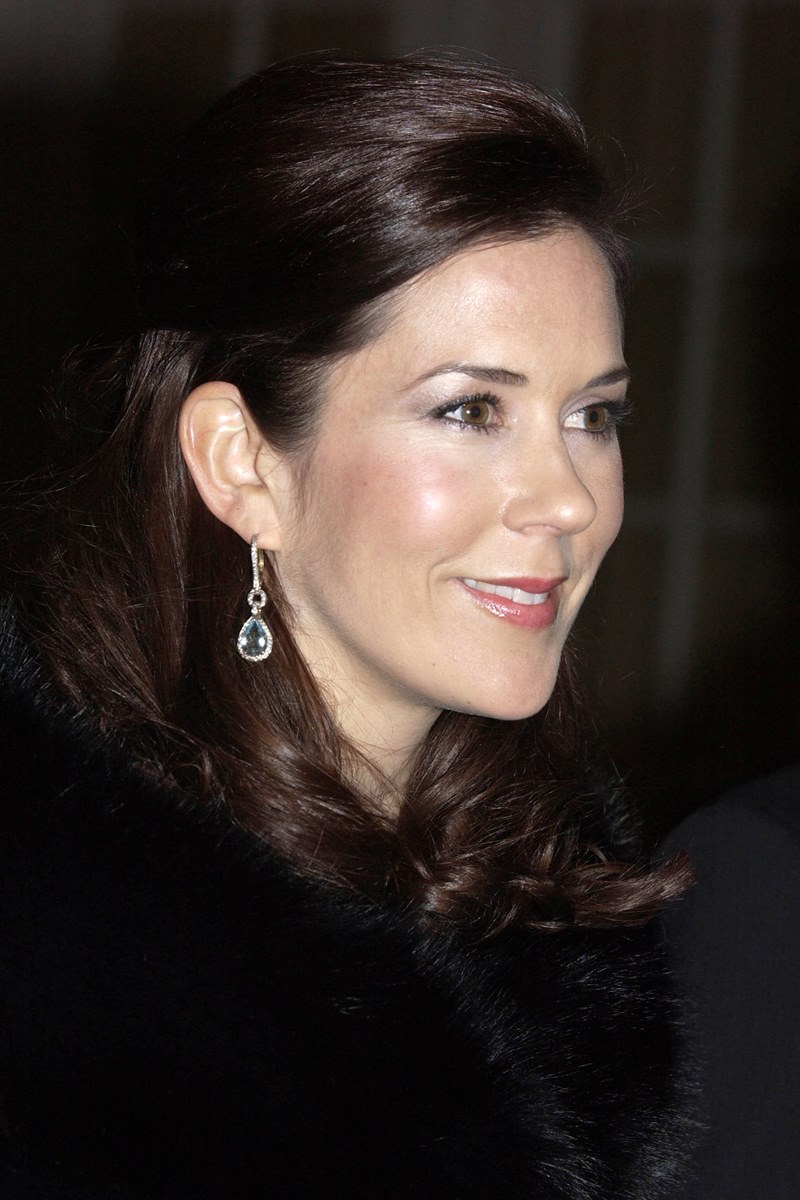 Foto colorida de mulher, com cabelo castanho solto. Ela usa um casaco preto e brincos - Metrópoles