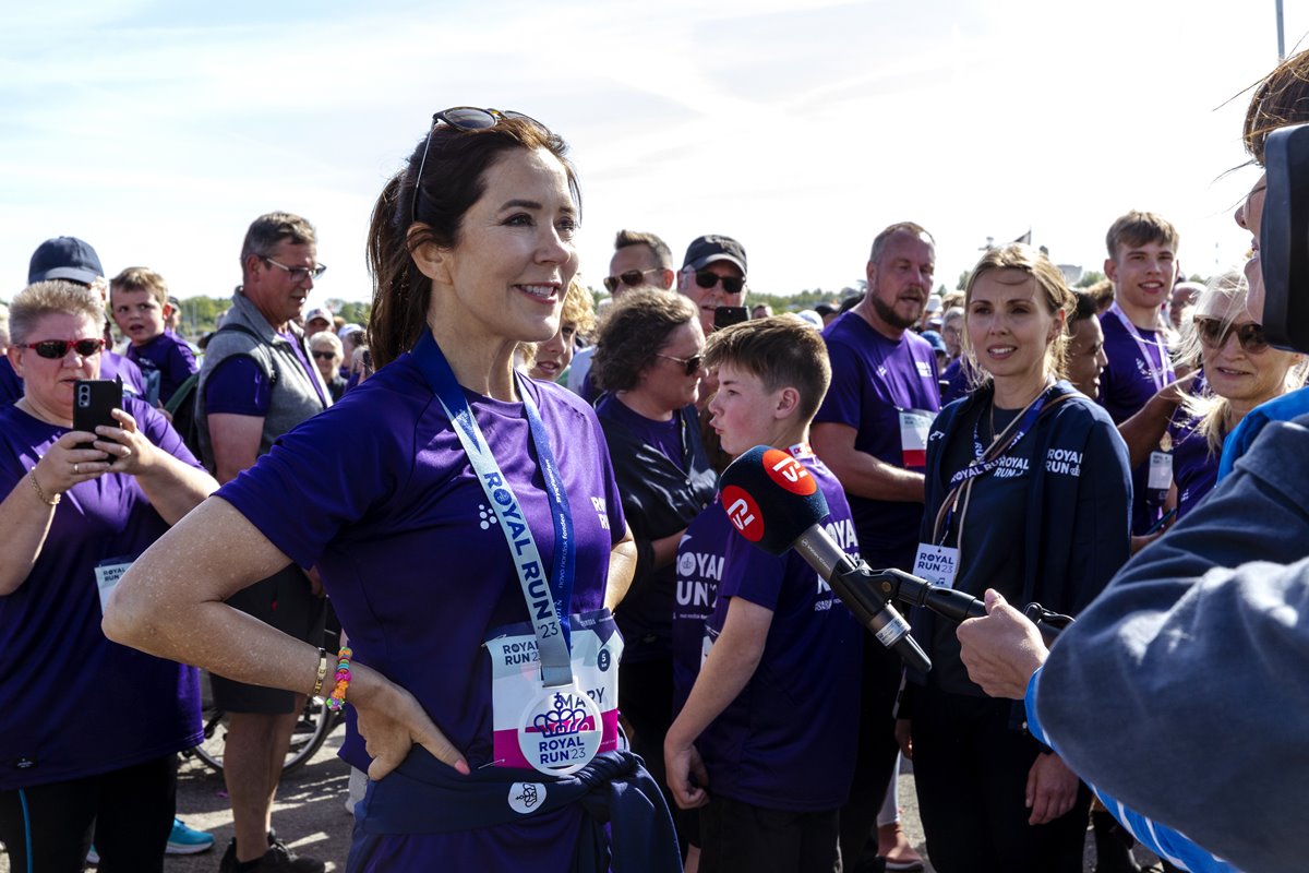 Foto de mulher com roupa de treino e medalha no pescoço. Ela está rodeada de crianças - Metrópoles