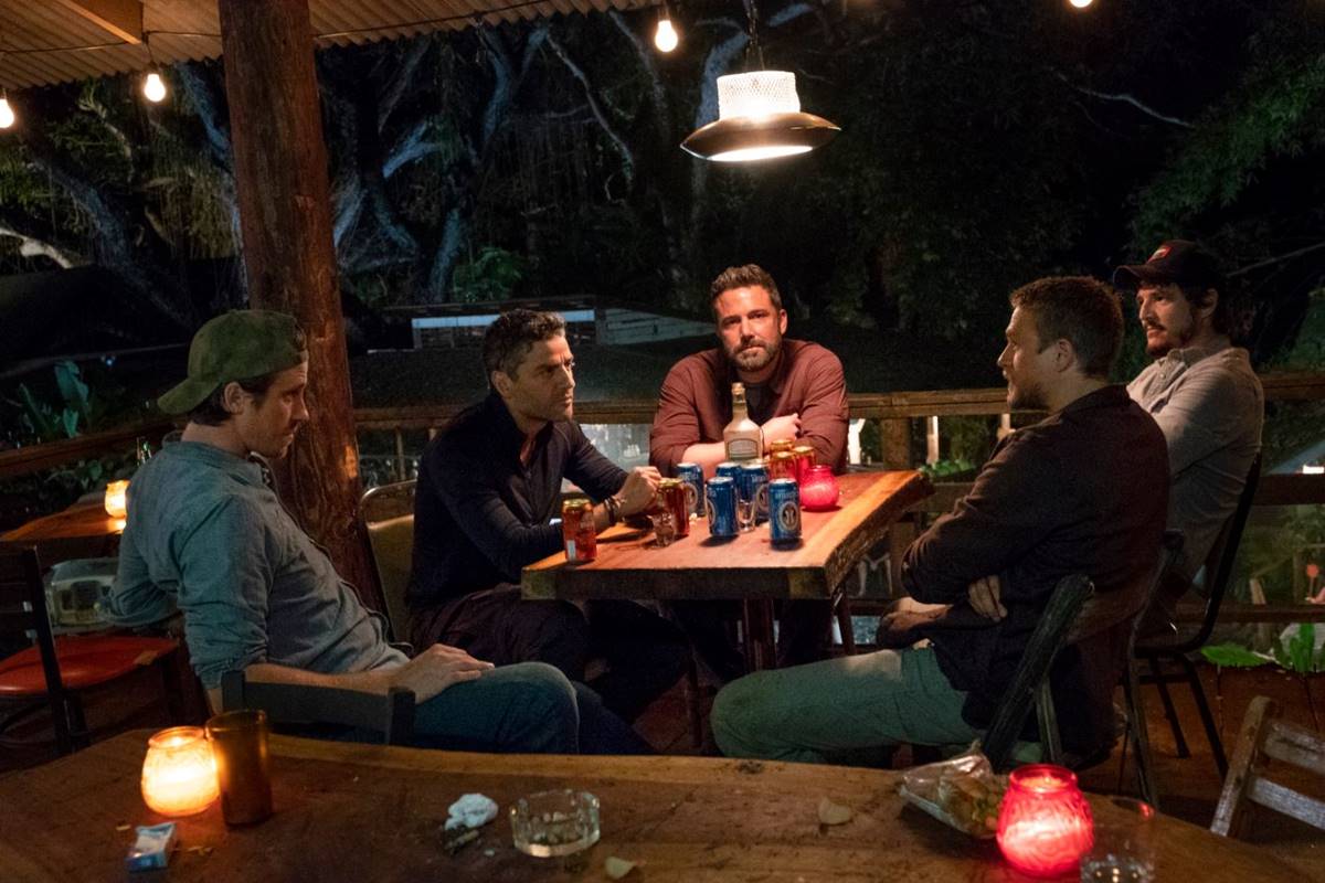 foto colorida de cinco homens sentados ao redor de uma mesa quadrada com latas de bebidas em cima - metrópoles