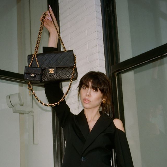 Mulher branca usa look preto segurando bolsas da Chanel - Metrópoles