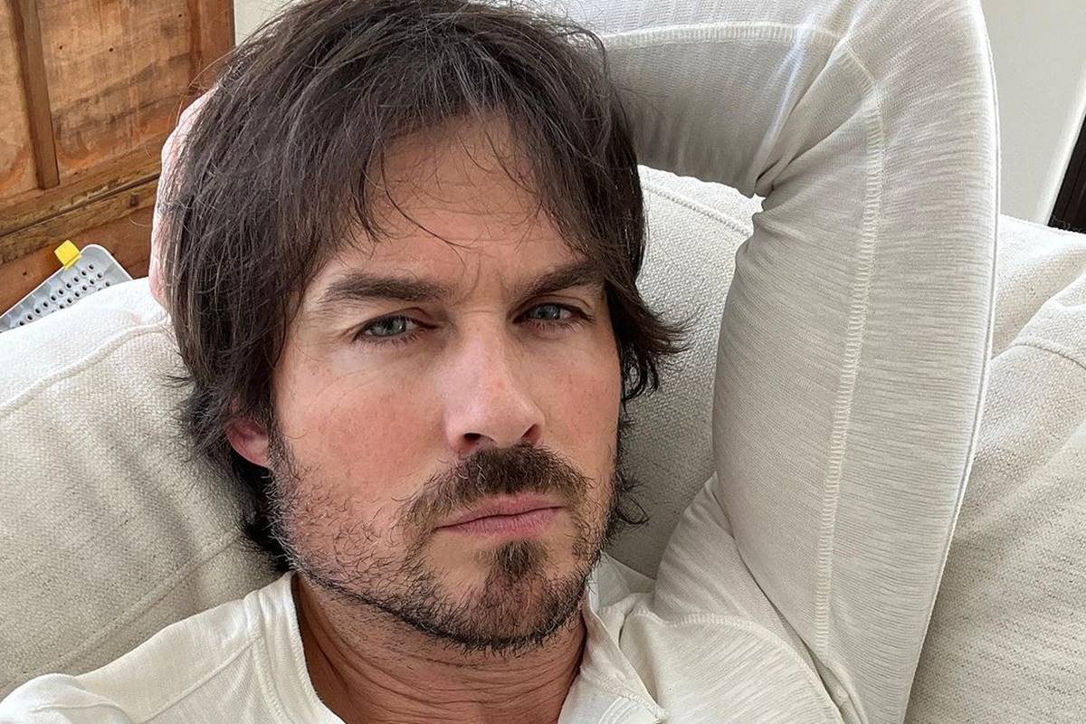 Foto colorida de Ian Somerhalder com blusa branca e deitado - Metrópoles