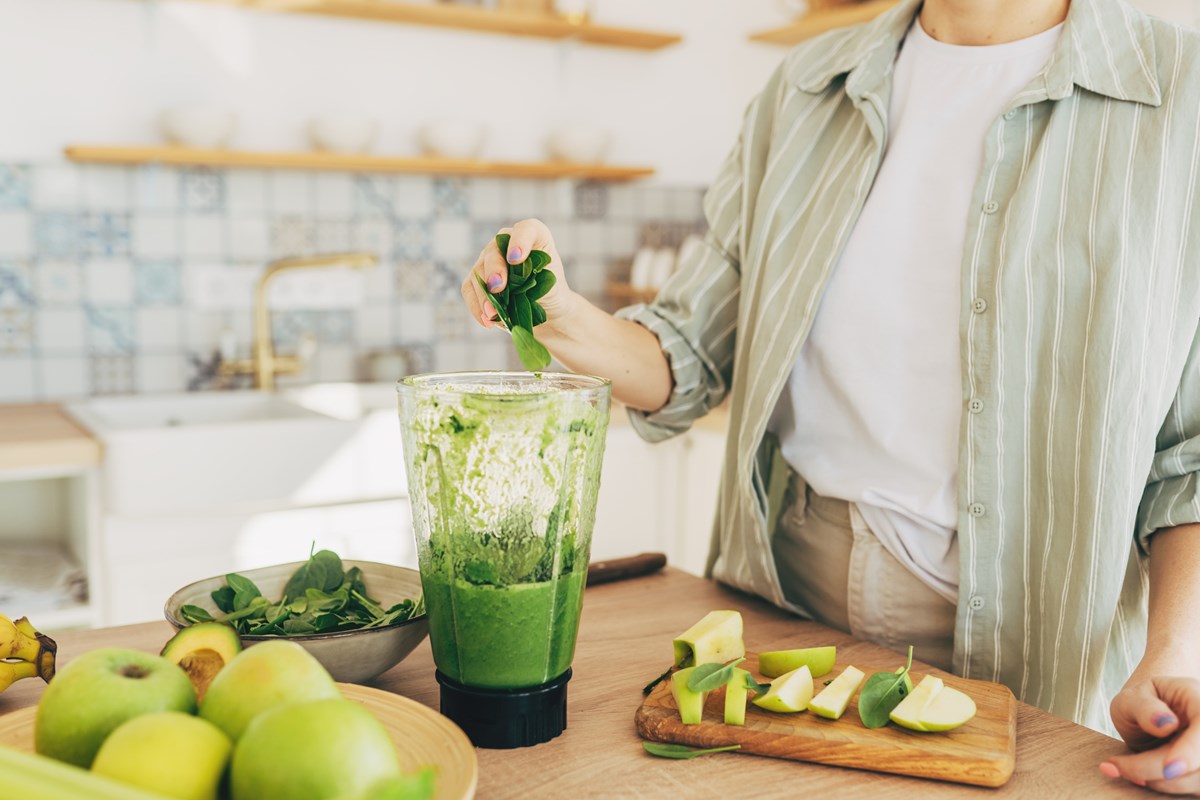 Mulher preparando suco verde saudável em cozinha - Metrópoles