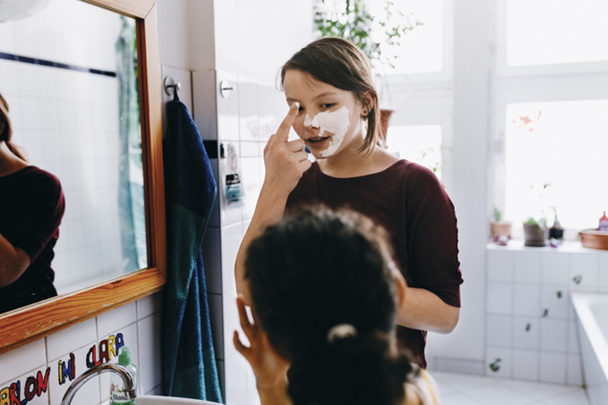 Adolescente passa creme facial em banheiro - Metrópoles