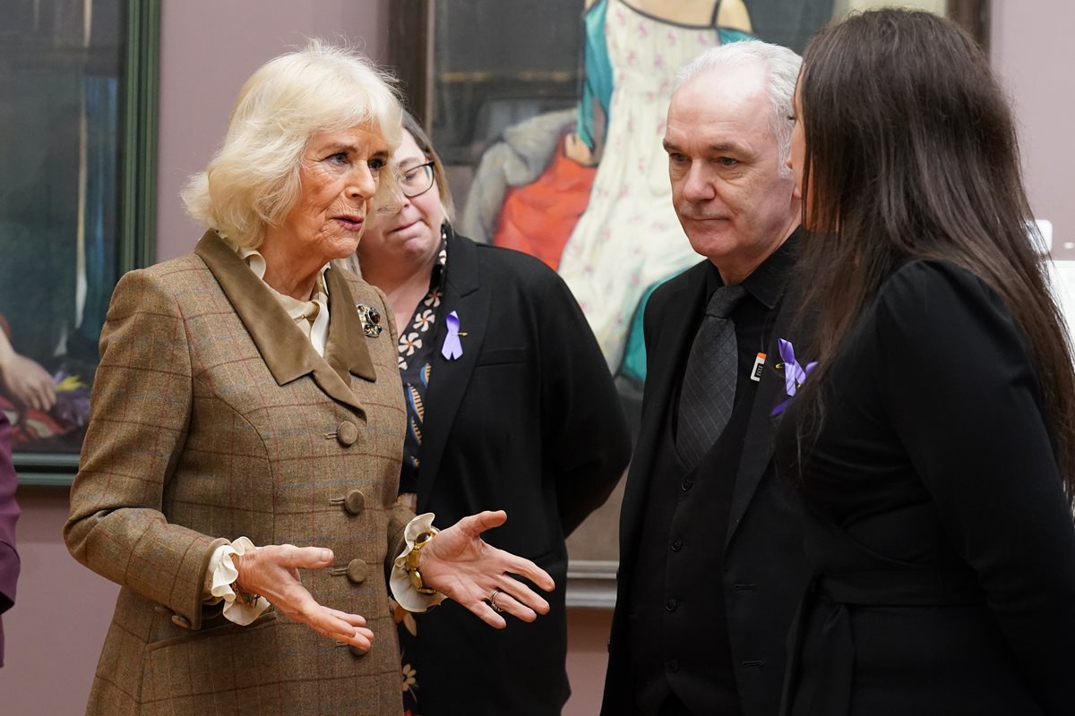 Foto colorida de mulher idosa com blazer. Ela está conversando com uma mulher e um homem, ambos vestidos com roupas pretas - Metrópoles