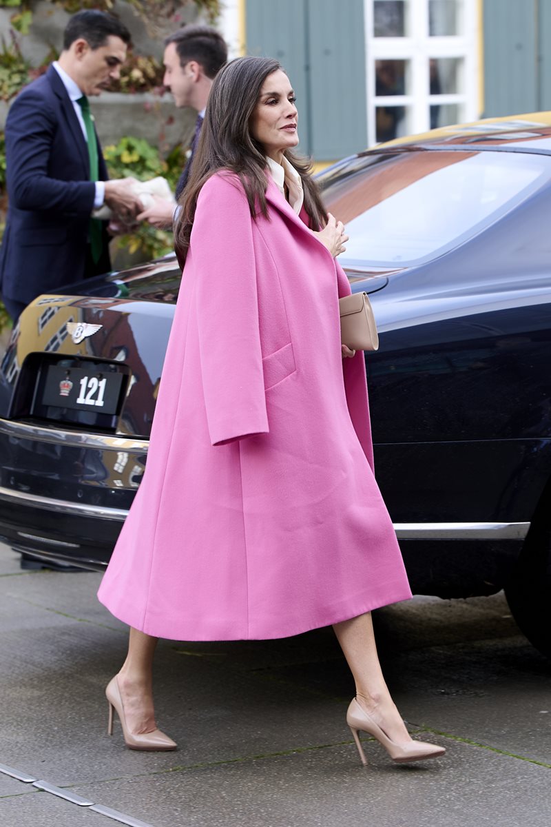 Foto de mulher com cabelo castanho, vestida com um casaco rosa. Ela está andando - Metrópoles