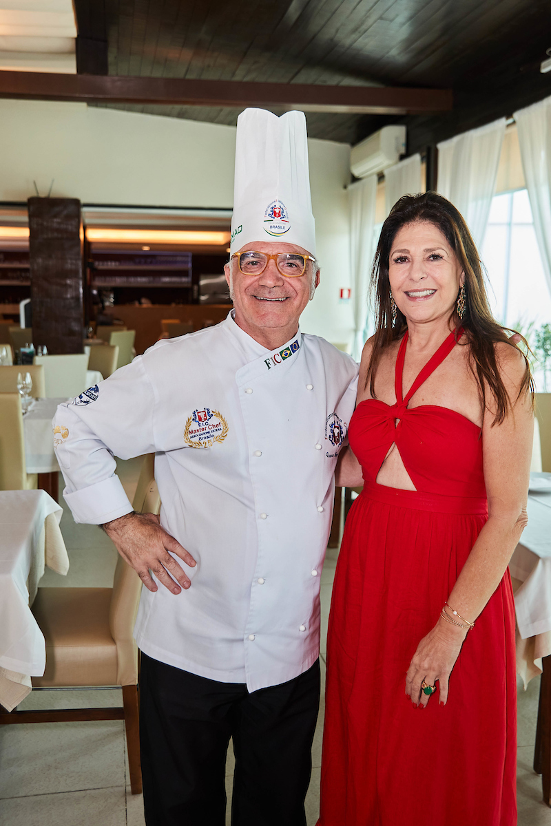 Chef de cozinha ao lado de mulher com vestido vermelho